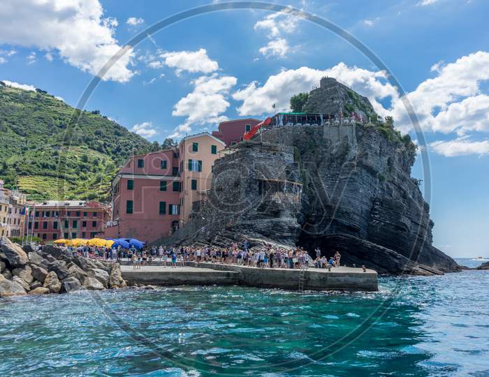 Vernazza, Cinque Terre, Italy - 26 June 2018: Tourist Sitting On A Rock Overlooking The Ocean At Vernazza, Cinque Terre, Italy