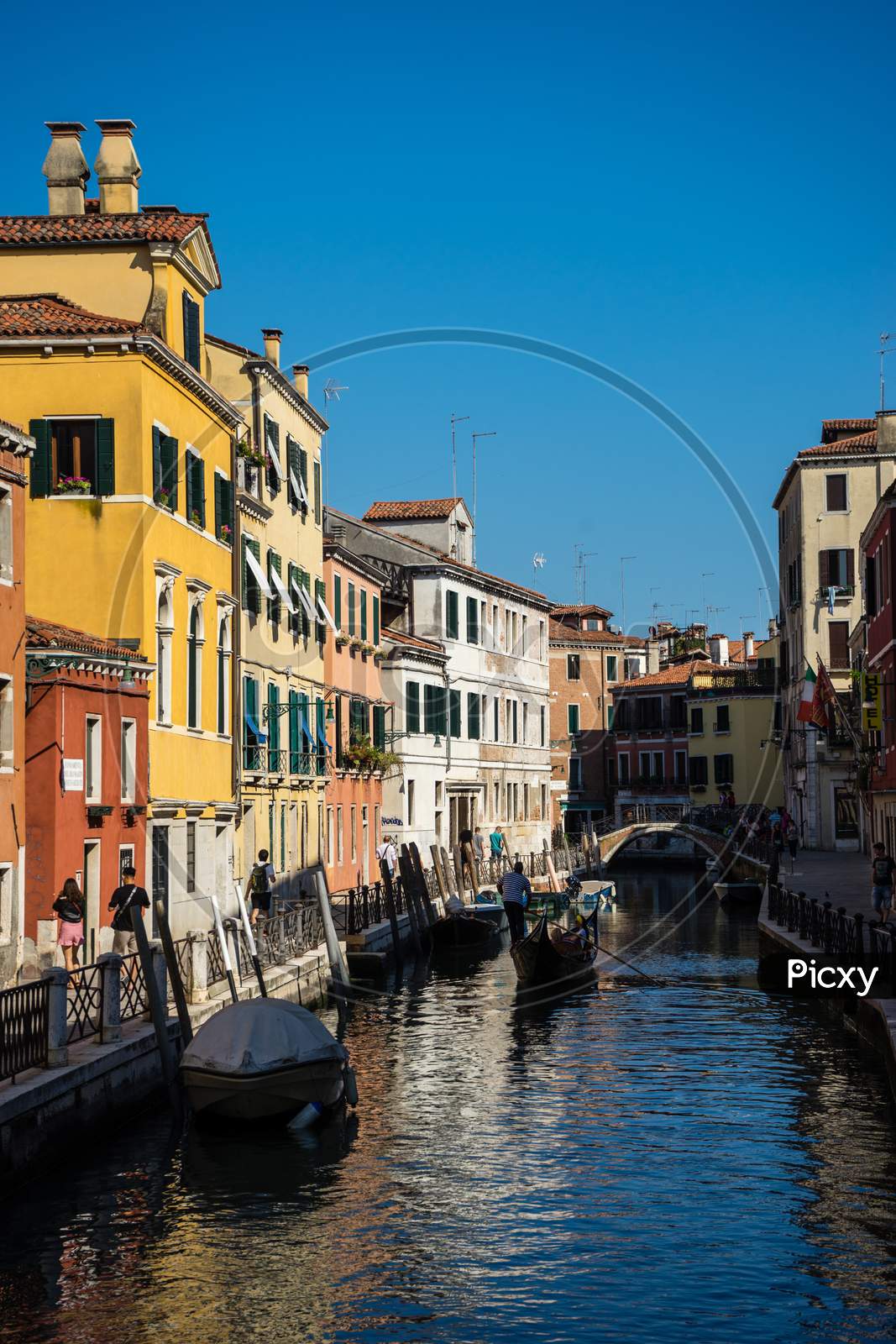 Venice, Italy - 30 June 2018: People Walking Down The Narrow Streets Of Venice Along A Canal, Italy