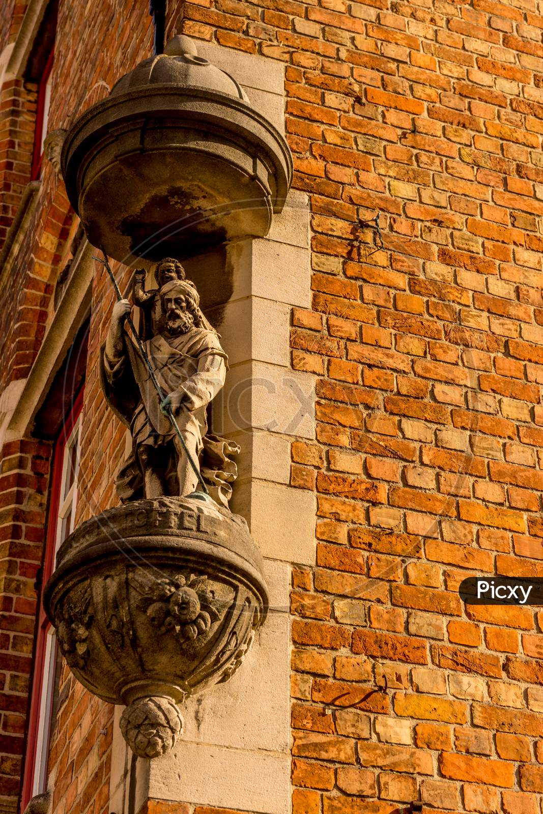 Belgium, Bruges, A Close Up Of A Brick Building With A Sculpture On A Wall