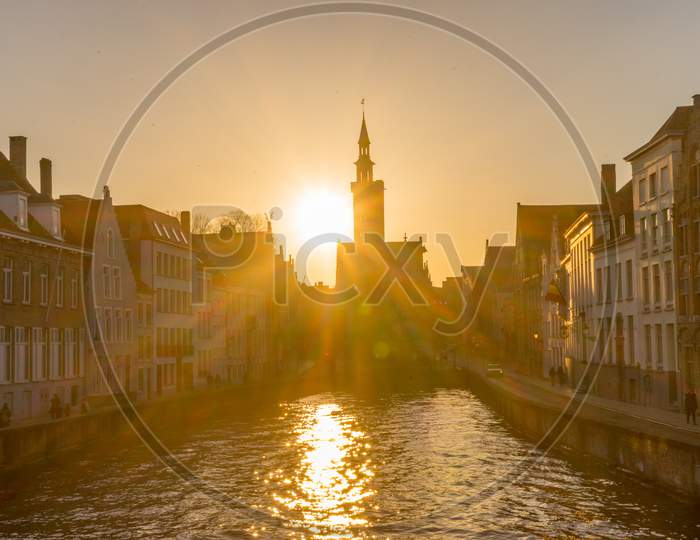 Belgium, Bruges, A Building With A Sunset In The Background At  De Spinolarei And Spiegelrei