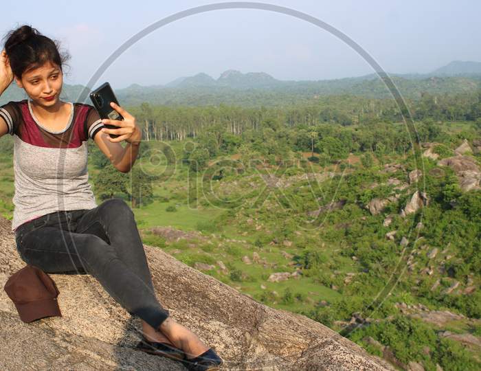 A young girl taking selfy in forest, cap