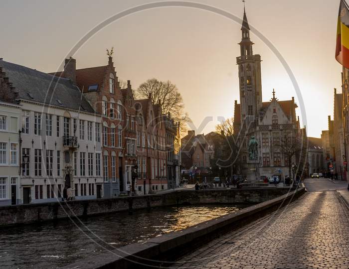 Belgium, Bruges, A Building With A Sunset In The Background At  De Spinolarei And Spiegelrei