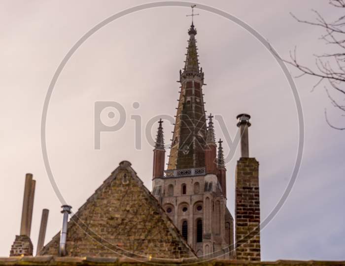 Belgium, Bruges, A Large Tall Tower With A Clock At The Top Of A Building