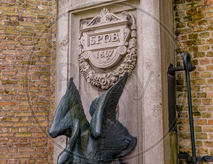 Belgium, Bruges, A Swan Statue In Front Of A Brick Building