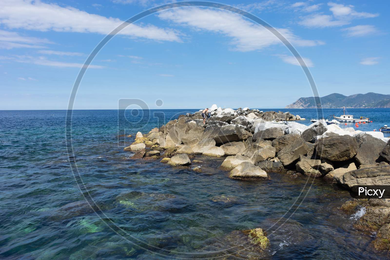 Italy,Cinque Terre,Riomaggiore, A Rocky Beach Next To A Body Of Water