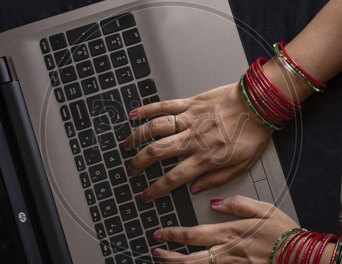 Female Wearing Bangles And Working On Laptop.