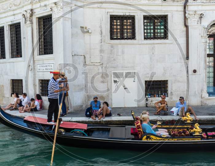 Venice, Italy - 30 June 2018: Gondolier Taking Tourists On A Gondola Ride Along The Grand Canal Near Fondamenta De La Preson In Venice, Italy