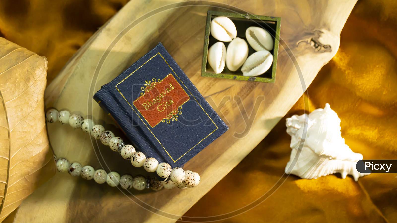 Hindu holy book and cowrie shell on a golden satin cloth with other elements of religious rituals