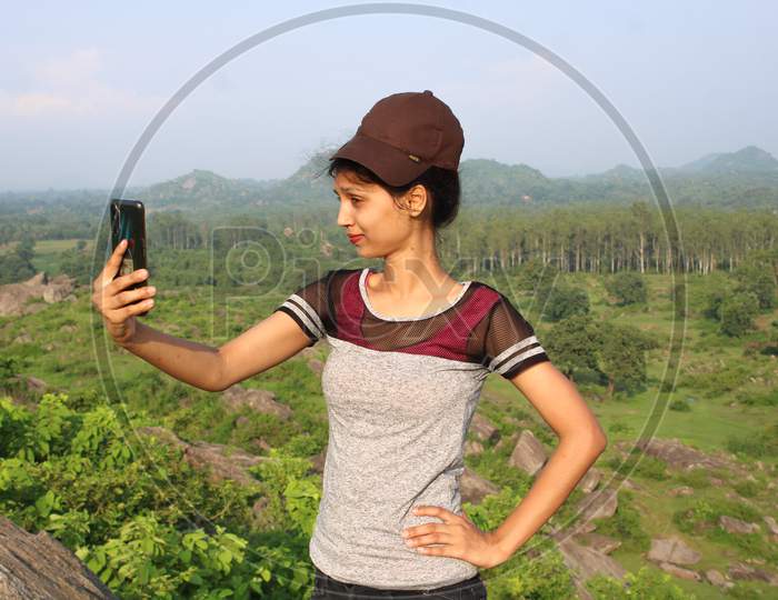 A young girl taking selfy in forest, cap
