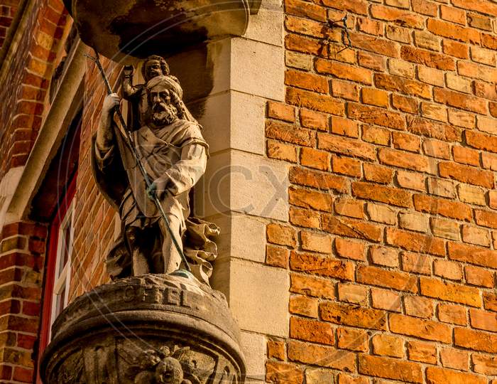 Belgium, Bruges, A Close Up Of A Brick Building With A Sculpture On A Wall