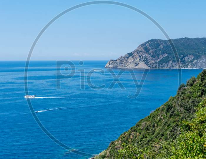 Italy, Cinque Terre, Corniglia, A Large Body Of Water With A Mountain In The Background