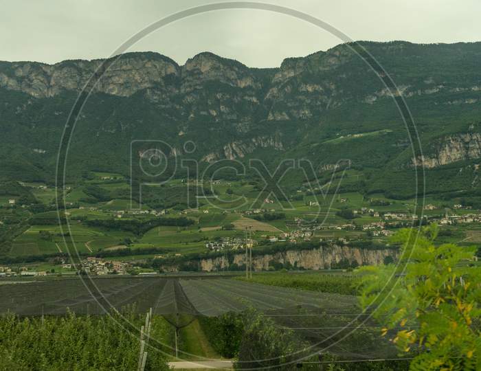 Italy,La Spezia To Kasltelruth Train, A Large Green Field With A Mountain In The Background