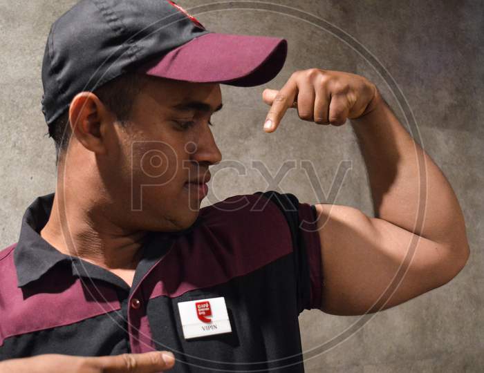 A Cafe Staff Showoff His Bicep In Cafe Uniform At Cafe Indoor.