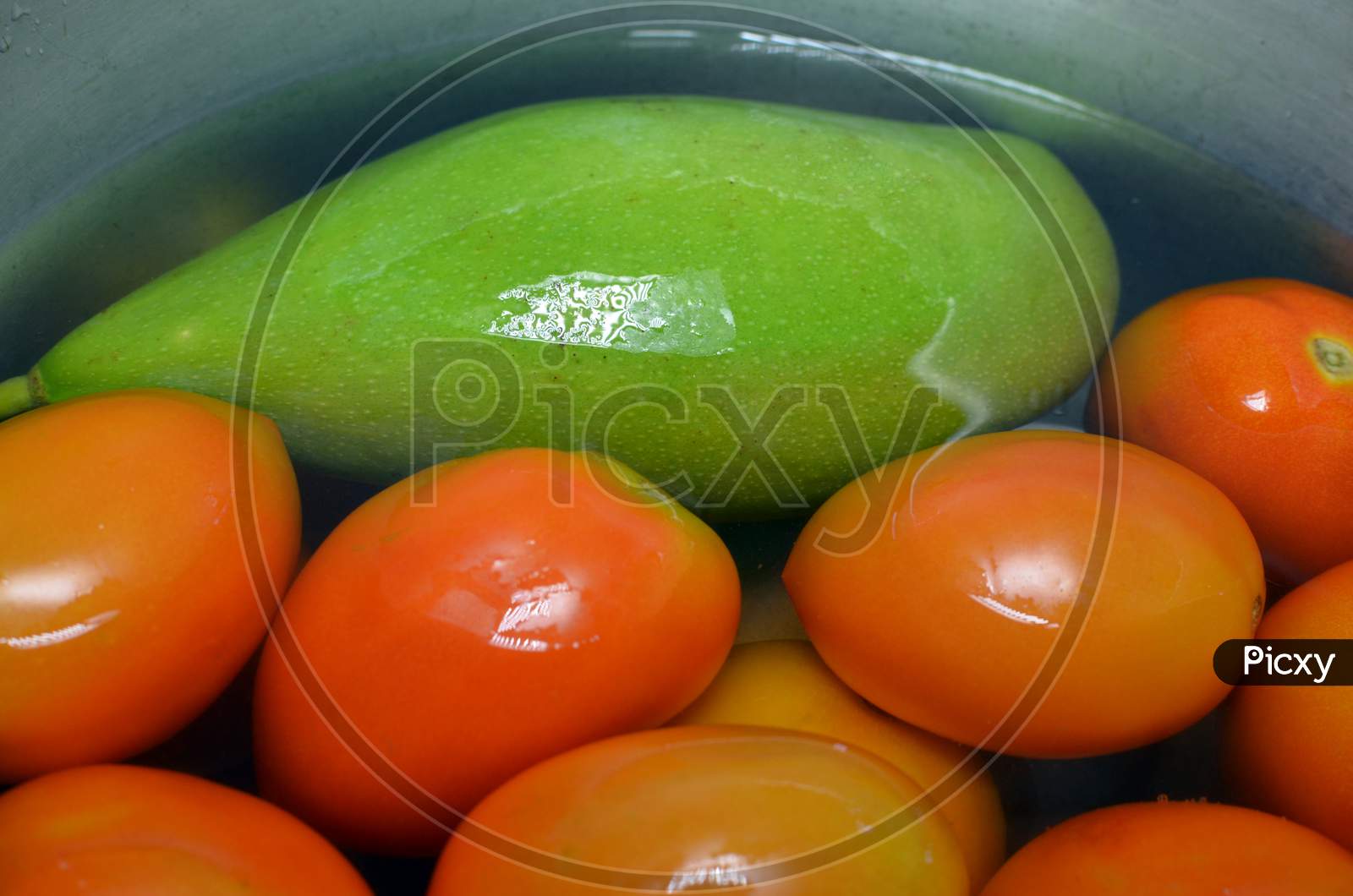 Raw Green Mango And Red Tomatoes In Water