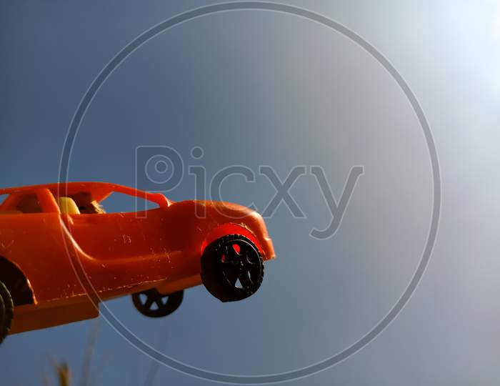 Red Color Toy Car Isolated On Blue Sky Background.