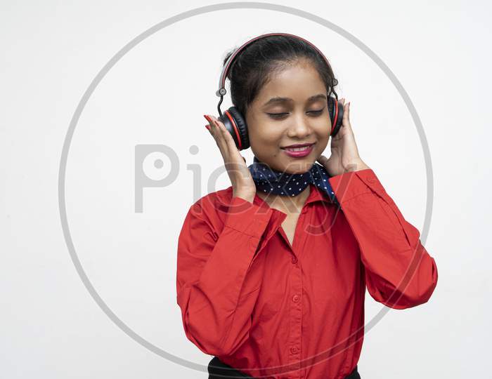 Young Charming Girl In Red Dress Enjoying Music In Her Red Headphones.