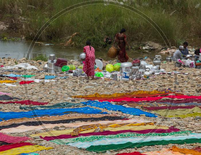 A Beautiful view of the native workers doing their daily chores of Washing clothes and Utensils by the river side near Mysuru in Karnataka/India.