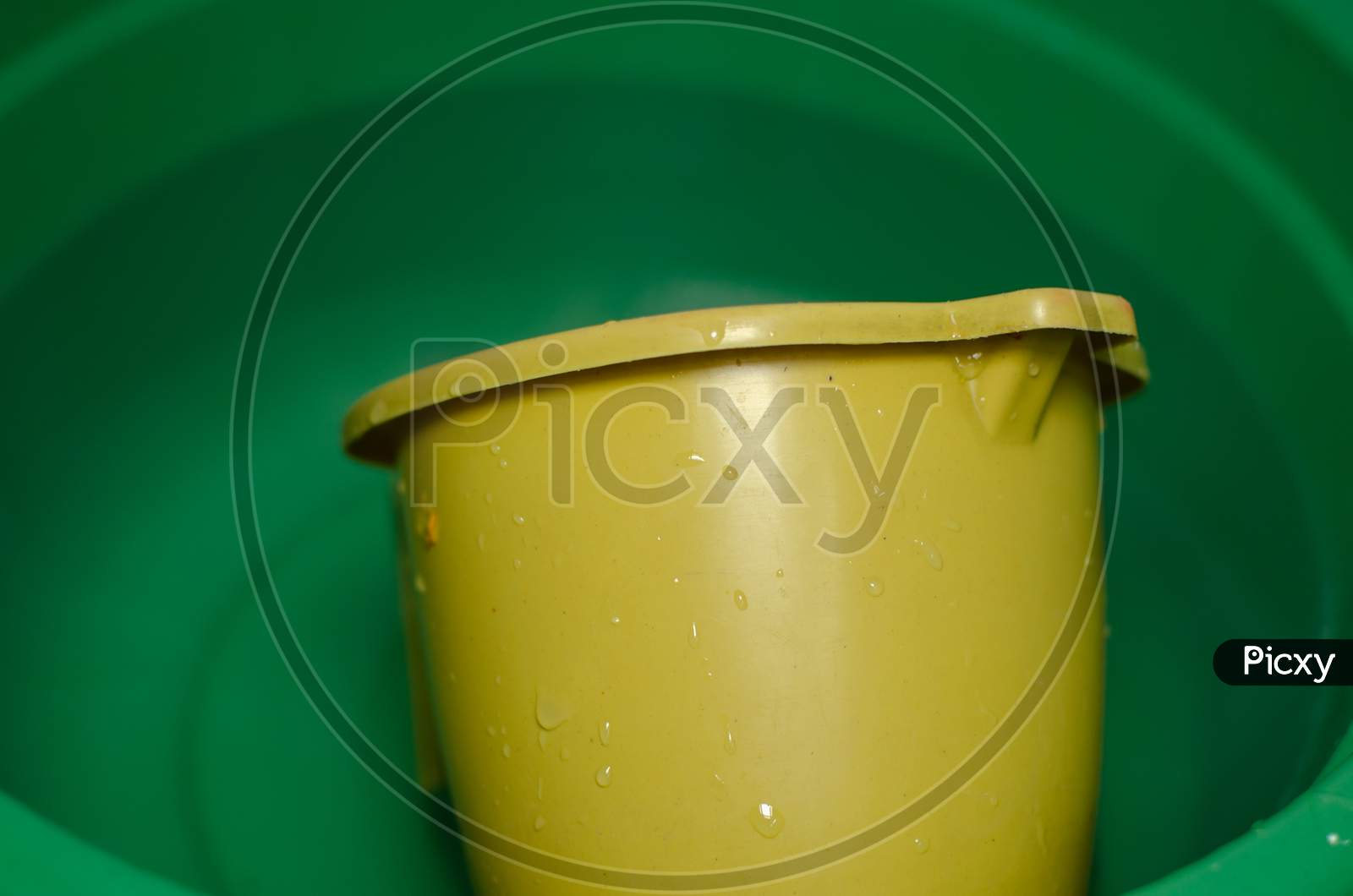 A Yellow Mug In A Green Water Tub