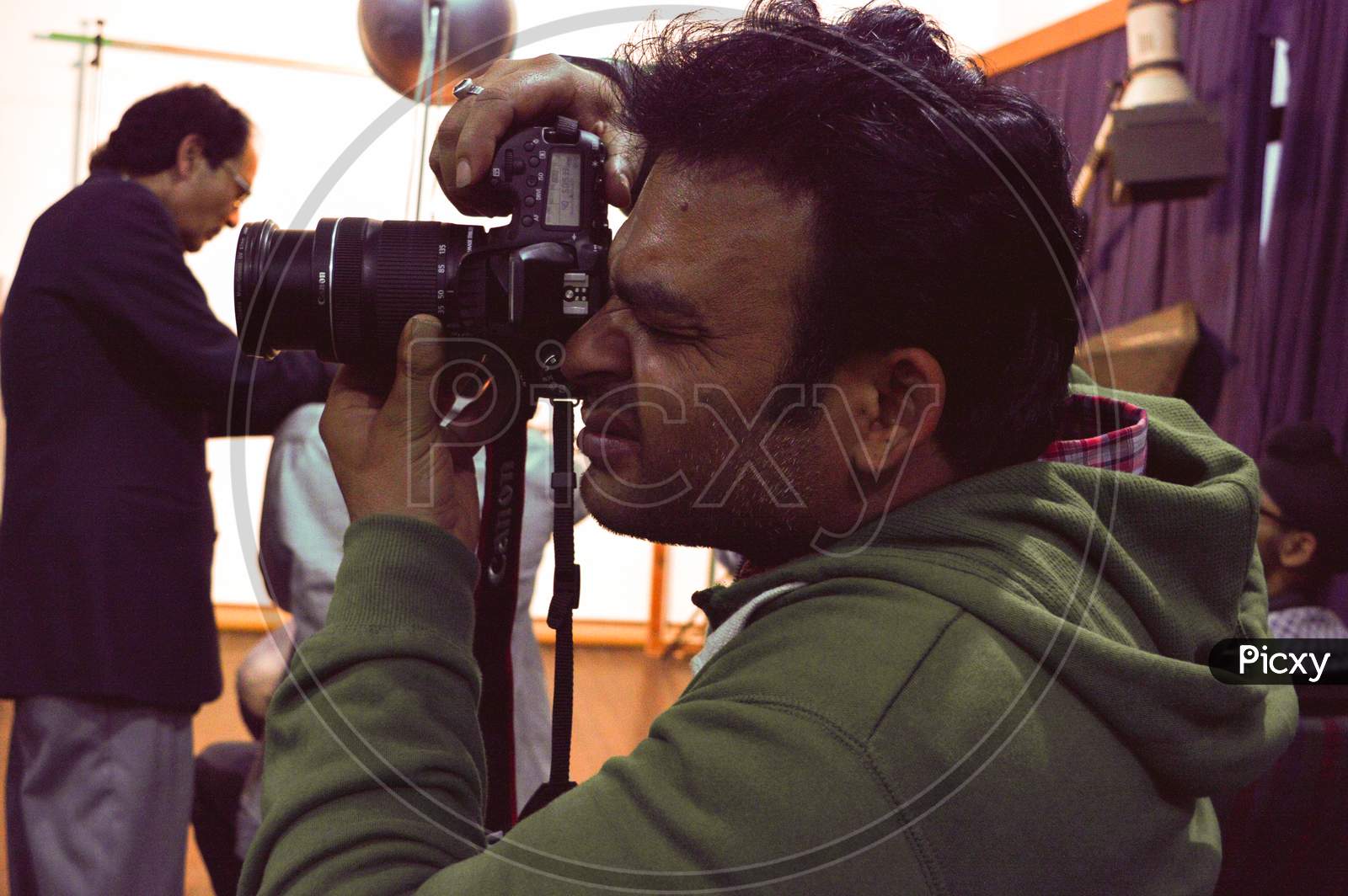 A Student Using Nikon Camera At Classroom Taking Portrait Of Others.