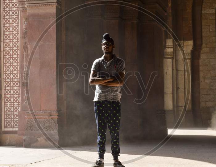 A Indian Boy Giving Pose For Fashion Shoot Inside Of Old Fort And Asi Employee Cleaning The Area.