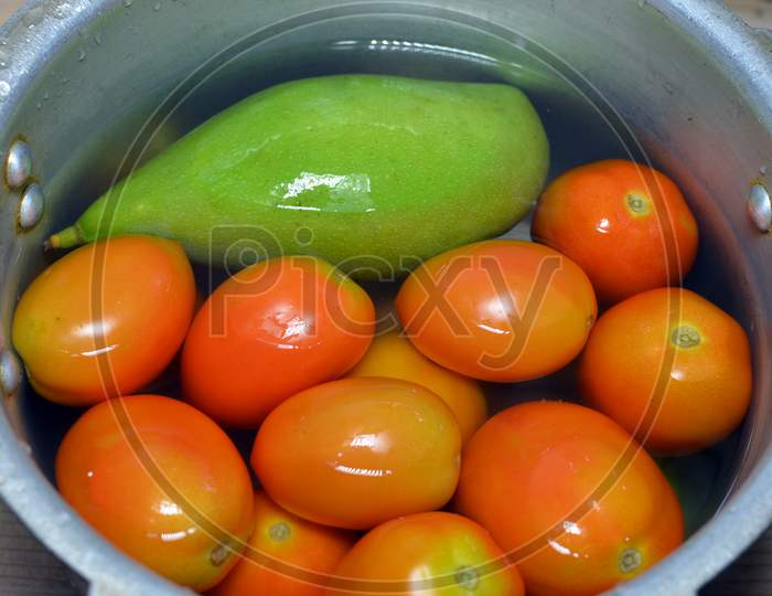 Raw Green Mango And Red Tomatoes In Water