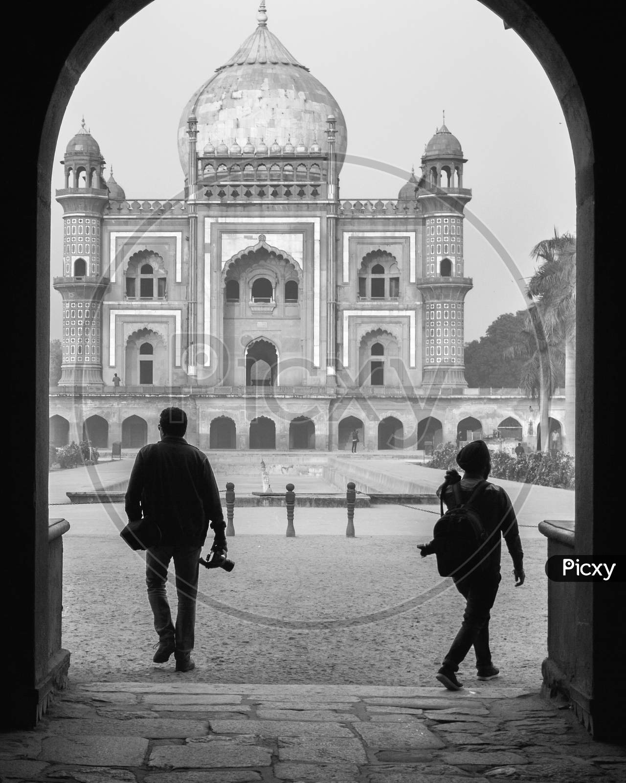 Two Photography Student Walking With Camera Trough The Main Gate,Entrance Of Safdarjung Tomb Memorial At Winter Morning Black And White Silhouette.