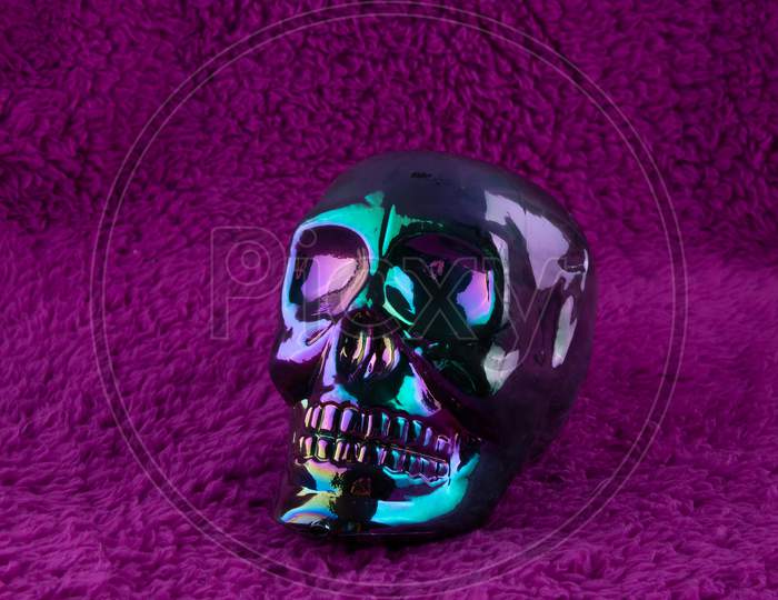 Shiny Iridiscent Skull On Fluffy Purple Background. Concept For Halloween.