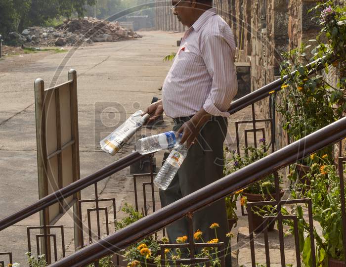A Men Is Collecting Empty Water Bottle From Lawn Which Is Thrown By Tourist At Old Fort.