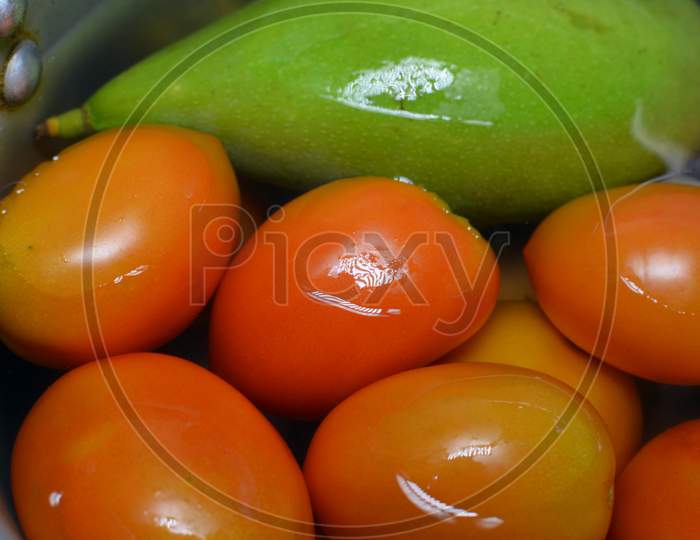 Close Up Shot Of Raw Green Mango And Red Tomatoes In Water