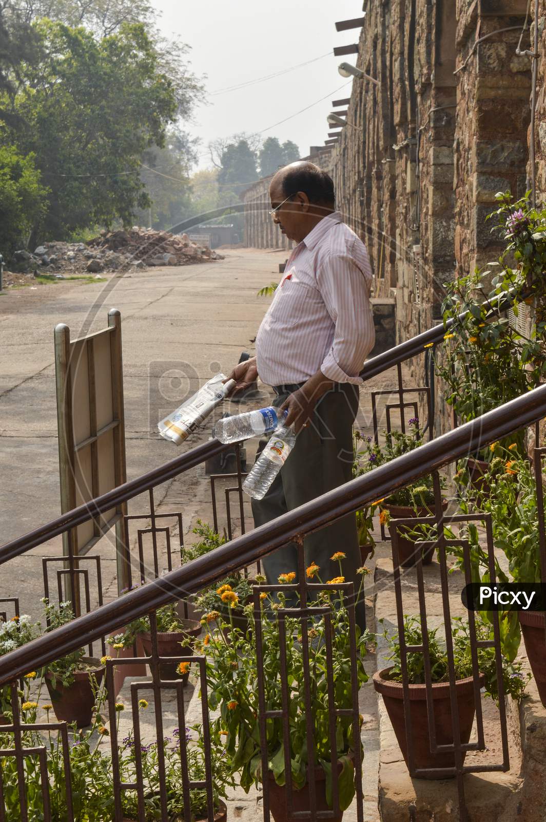 A Men Is Collecting Empty Water Bottle From Lawn Which Is Thrown By Tourist At Old Fort.