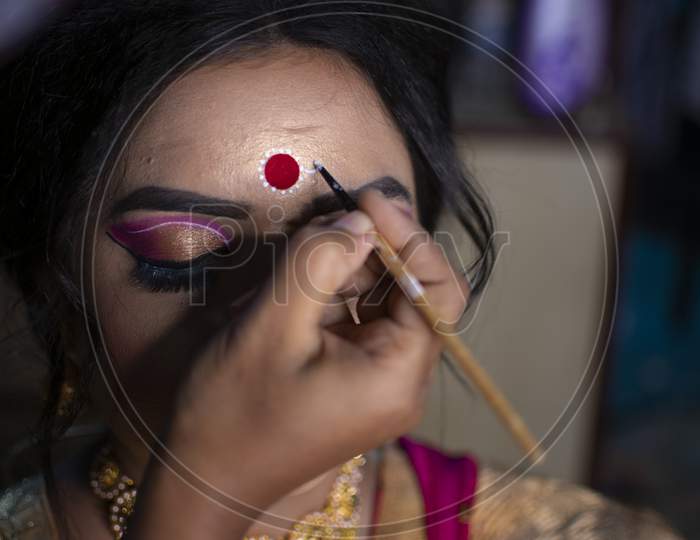 A Makeup Artist Drawing A Beautiful Design Called Kolka Or Bindi In India On The Forehead Of A Bride