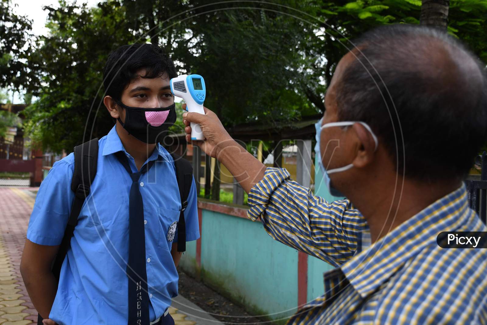 A student  gets his  body temperature checked at the entrance gate of a school as schools reopened after more than 5-months closure due to the Covid-19 coronavirus pandemic in  Nagaon District of Assam on  sep 21,2020.