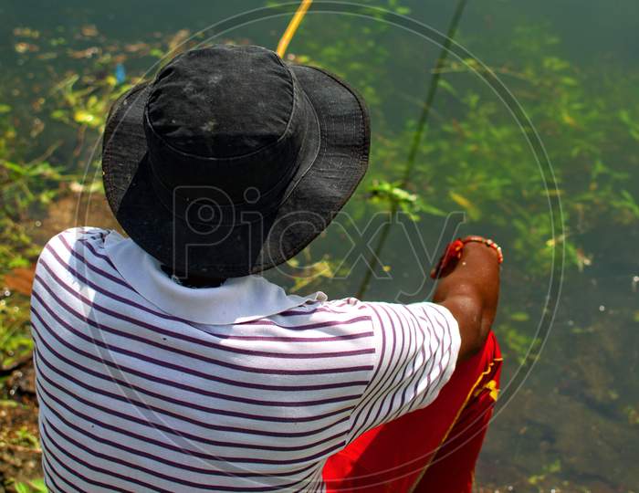 A Person Is Sitting Near River To Catch Fish