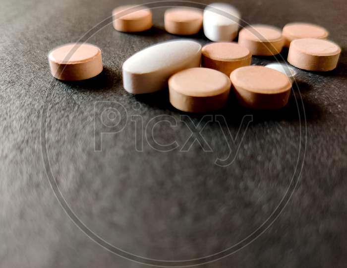 Concept Of Tablets.Covid-19 Corona Virus Cure.White And Orange Color Medical Pills On Black Background.