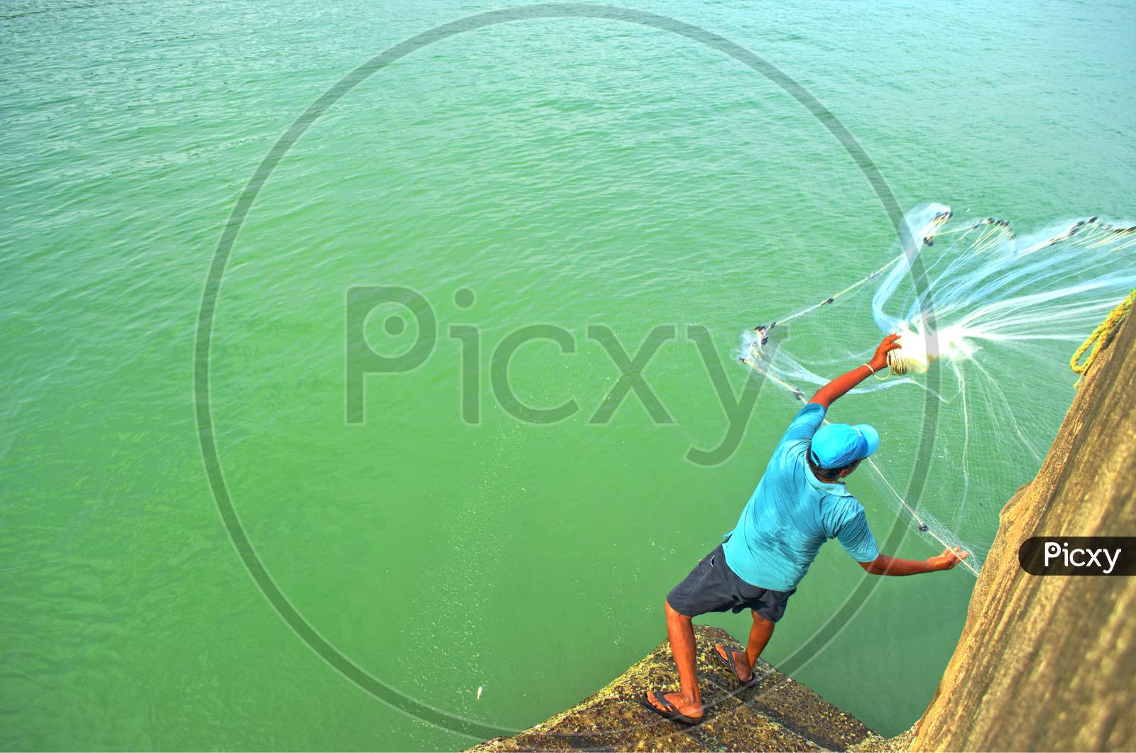 Fisherman Spreading His Net In Sea To Catch Fish