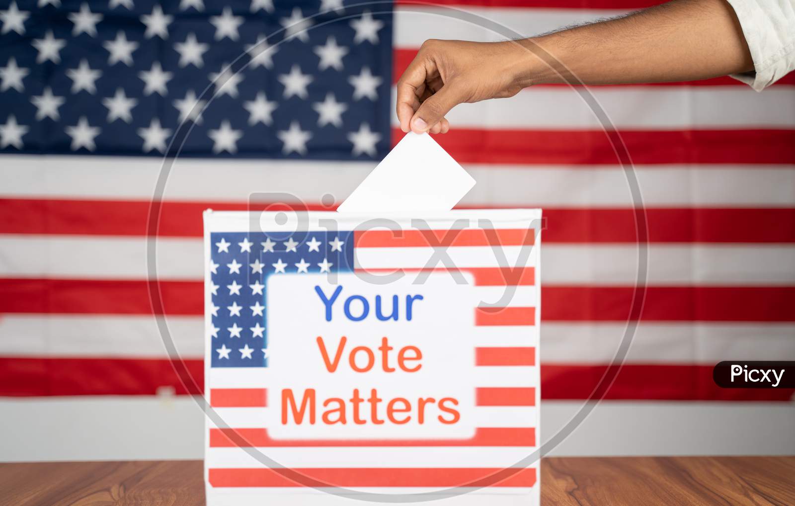 Close Up Of Hands Placing Vote Inside The Ballot Box With Your Vote Matters Printed With Us Flag As Background - Concept Of Voter Rights And Us Election.