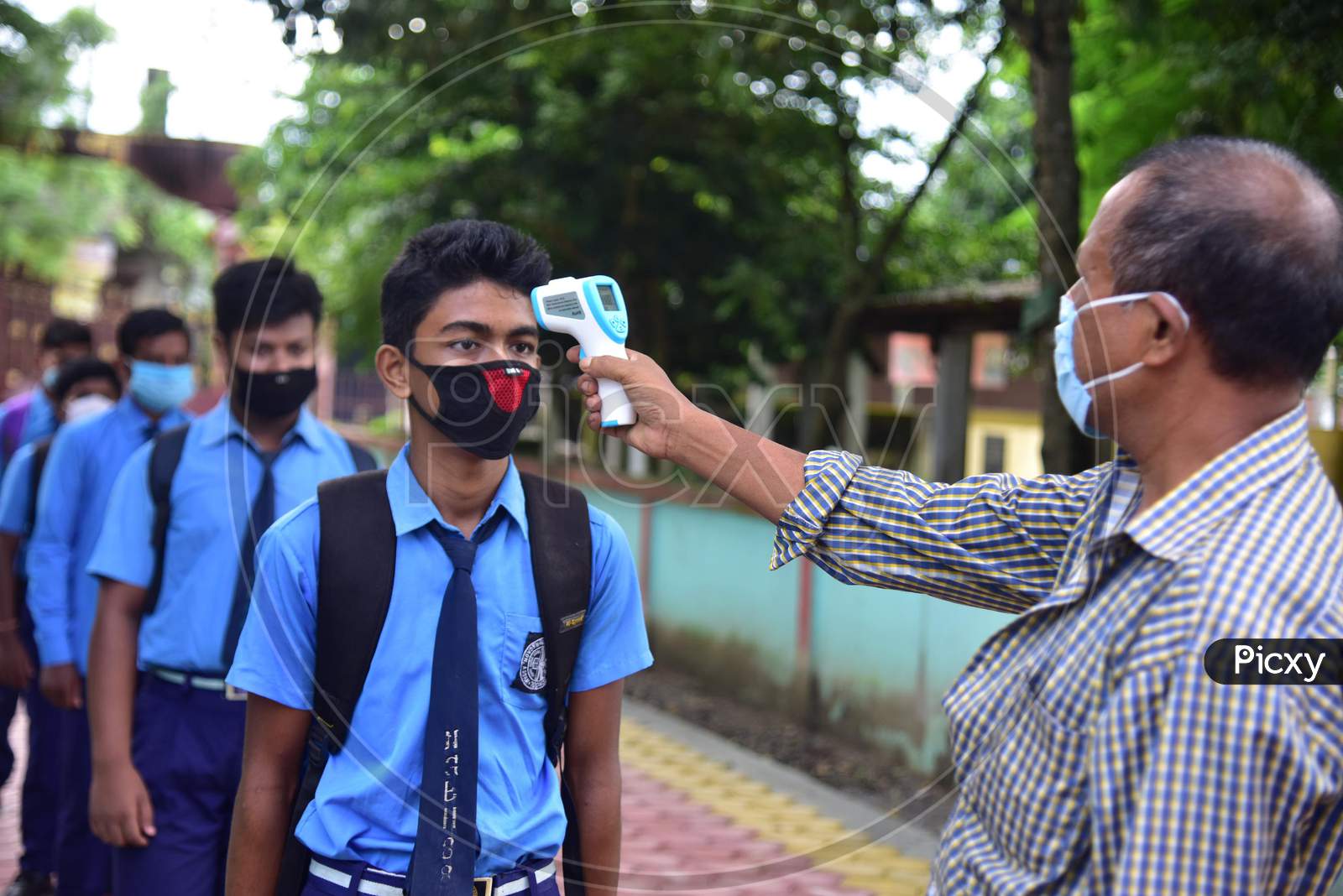 A student gets his body temperature check at the entrance gate of a school as schools reopened after more than 5-months closure due to the Covid-19 coronavirus pandemic in  Nagaon District of Assam on  sep 21,2020.
