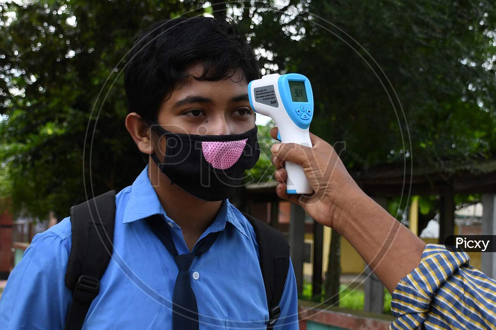 A student  gets his  body temperature check at the entrance gate of a school as schools reopened after more than 5-months closure due to the Covid-19 coronavirus pandemic in  Nagaon District of Assam on  sep 21,2020.