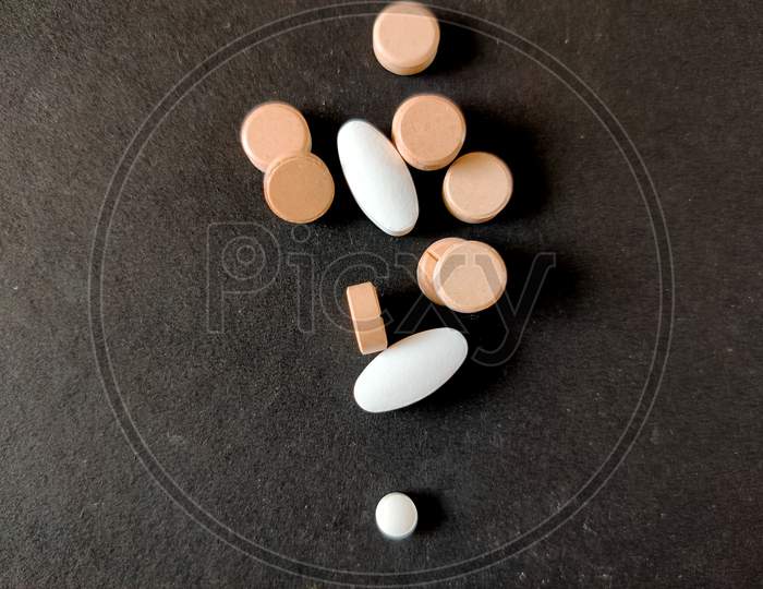 Concept Of Tablets.Covid-19 Corona Virus Cure.White And Orange Color Medical Pills On Black Background. Selective Focus