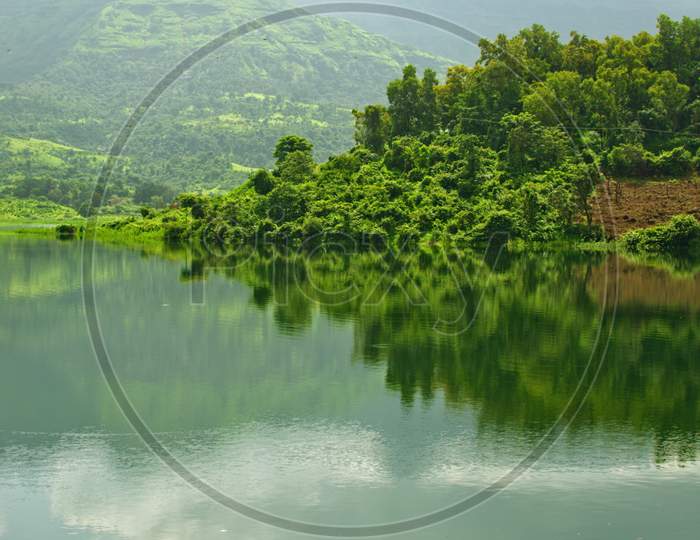 Reflection Of A Hill Covered With Green Trees