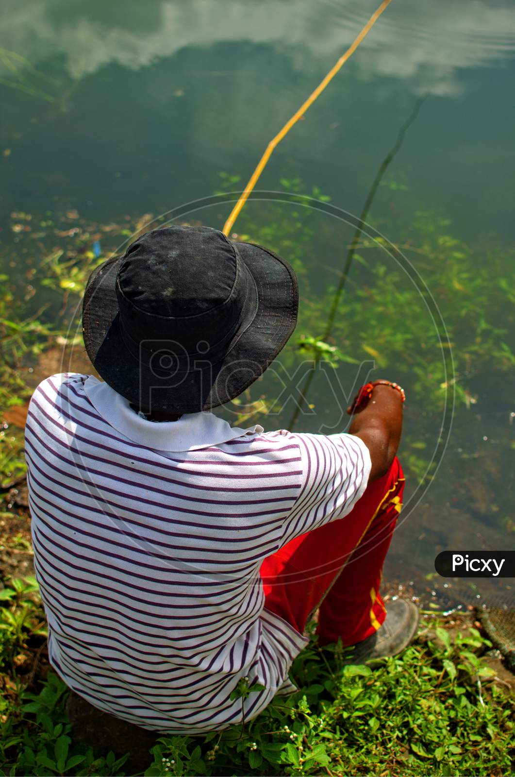 A Person Is Sitting Near River To Catch Fish