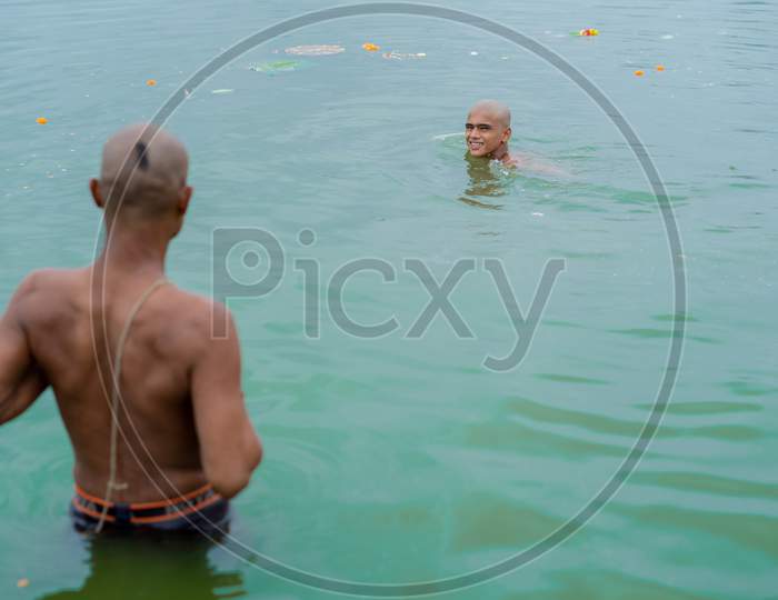 A hindu devotee looking at who is smiling and taking bath in powai lake