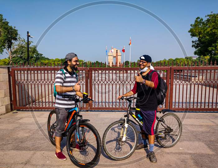 Two friends celebrating their long morning ride in front of National War Memorial/India Gate, New Delhi, India.