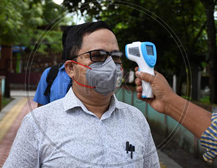 A teacher gets his body temperature check at the entrance gate of a school after schools and colleges reopened after more than 5-months closure due to the Covid-19 coronavirus pandemic in  Nagaon District of Assam on Sep21,2020.