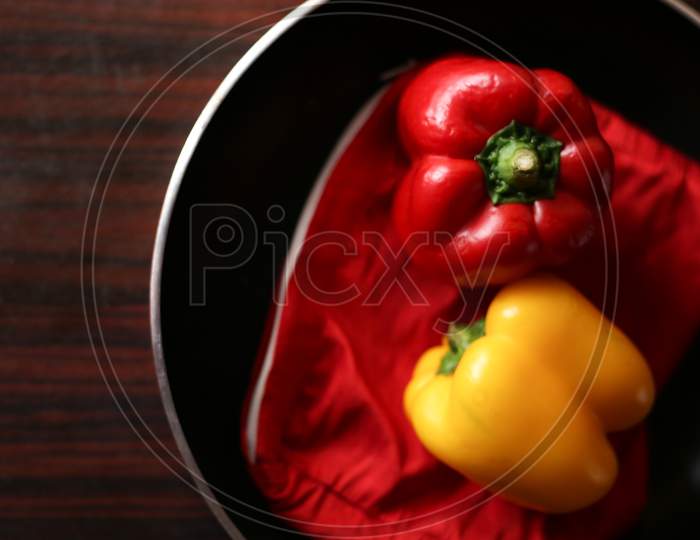 Closeup View Of Red And Yellow Color Bell Peppers In Cooking Pan With Wooden Background