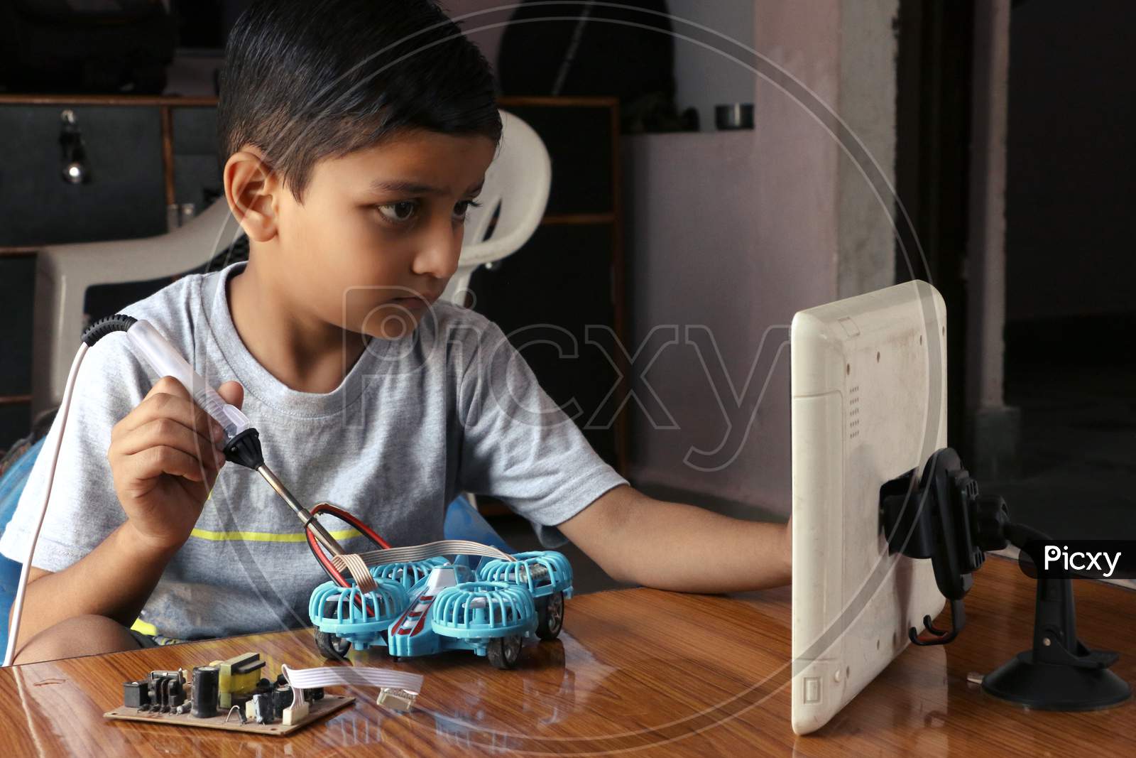 An 8 year old kid learning to make electric drone in kids online coding class. A child working with soldering iron. concept kids coding classes.  online coding class with tablet.