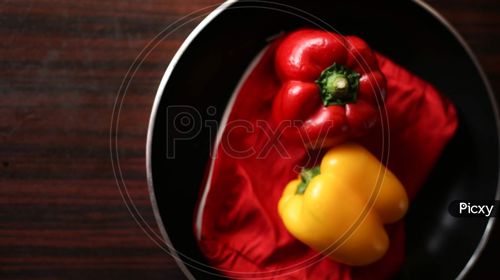 Closeup View Of Red And Yellow Color Bell Peppers In Cooking Pan With Wooden Background