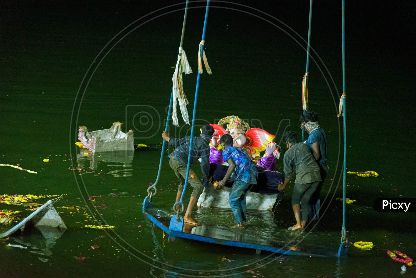 Group of people pushing the ganesh idol into the hussaina sagar to immerse ,hyderabad 2020