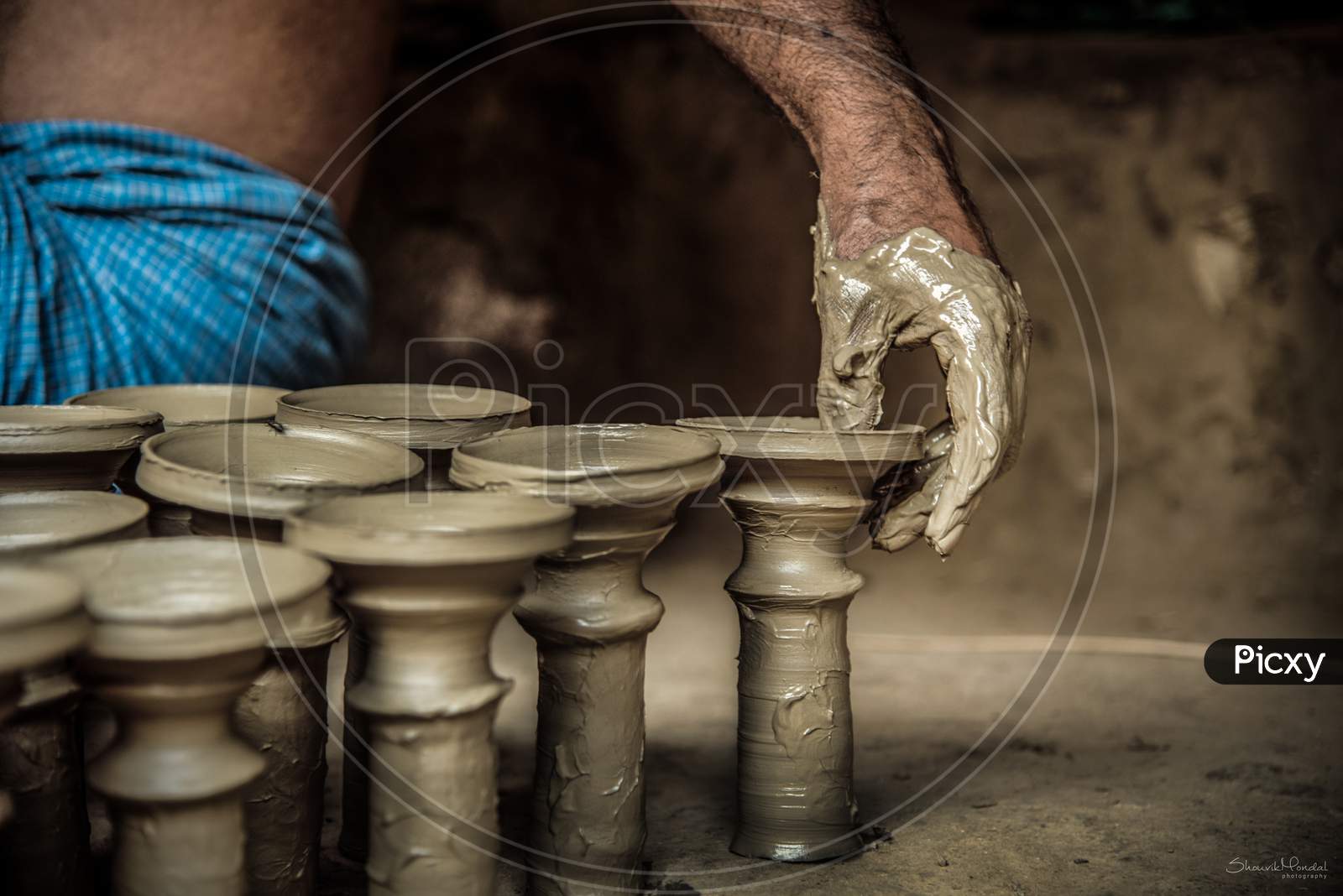 Hands of making clay pot on the pottery wheel ,select focus, close-up.