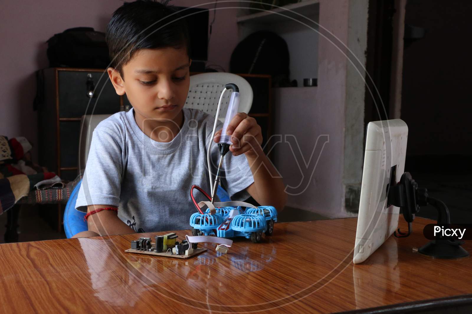 An 8 year old kid learning to make electric drone in kids online coding class. A child working with soldering iron. concept kids coding classes.  online coding class with tablet.